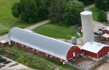 silo and a red barn on a farm with trees and fields in the background