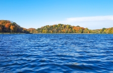 Autumn trees surround a blue, wavy lake.