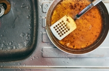 An overhead view of a spatula in a pot filled with grease sitting alongside a sink