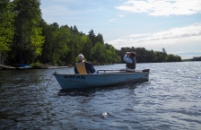 Two men in a blue fishing boat on a lake.