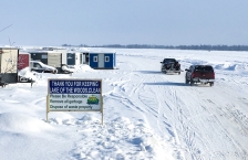Icehouses and pickups on frozen Lake of the Woods. A sign says "Thank you for keeping Lake of the Woods clean."