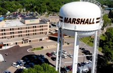 Aerial view of a white water tower with the name "Marshall" painted on it. 