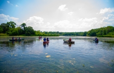 People in four canoes and a small fishing boat on a lake.