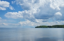 Blue sky with puffy white clouds over a large, still lake.