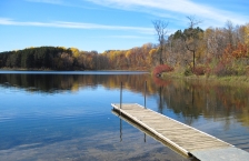 Dock extending into calm lake in the autumn.