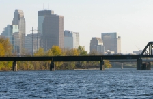 Railroad bridge crossing the Mississippi River with the Minneapolis skyline in background.