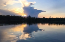 Cloud shaped like Minnesota is reflected in a calm lake.