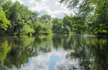 A wide, calm river reflecting the trees and sky.