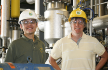 Two people in an industrial setting wearting hard hats