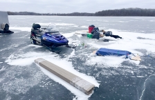 A snowmobile sits next to a pile of garbage on the ice.