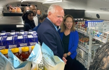 People standing in a bus lined with shelves full of food.