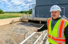Worker stands in front of an aeration tank at a wastewater treatment plant.