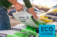 A man lifts a bag of water softener pellets from a pile of bags.