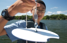 Young man holds a white secchi disk close to the camera lens