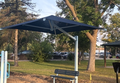 A blue shade canopy protects a bench at Ainsworth Park in St. Louis Park, Minnesota.