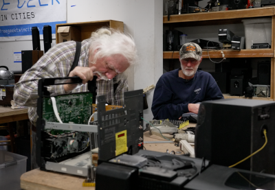 A Free Geek volunteer and community member sit together and examine a broken stereo