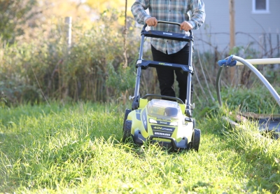 Person cutting grass with an electric lawnmower