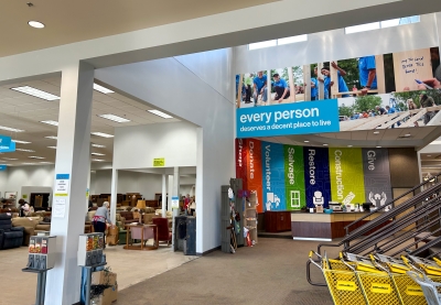 Open retail space selling used furniture. A large sign reads "every person deserves a decent place to live."