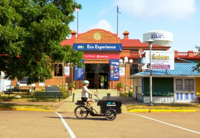 A person riding a cargo e-bike in front of the Eco Experience building at the Minnesota State Fair