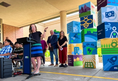 Commissioner Katrina Kessler speaking at a podium, Governor Tim Walz and Lt. Governor Peggy Flanagan stand in the background.