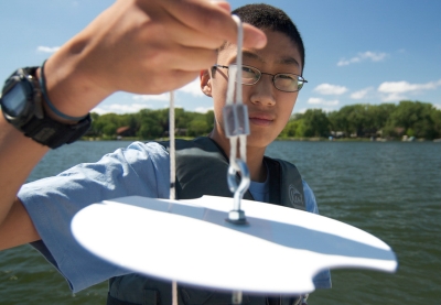 Young man holds a white secchi disk close to the camera lens