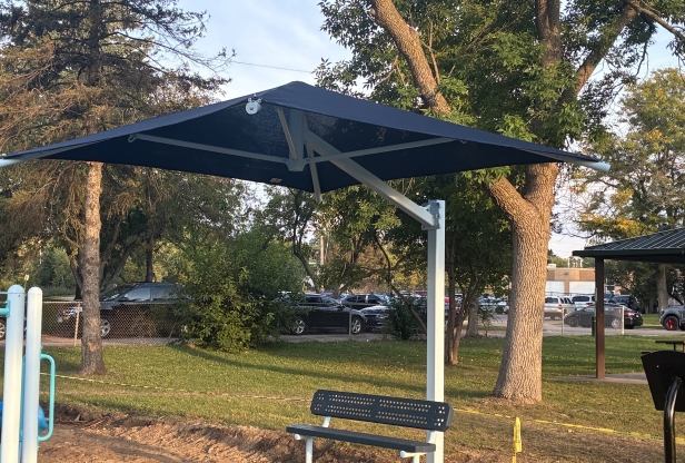 A blue shade canopy protects a bench at Ainsworth Park in St. Louis Park, Minnesota.