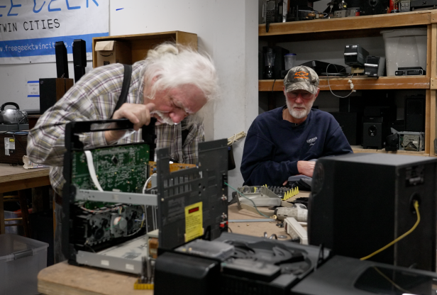 A Free Geek volunteer and community member sit together and examine a broken stereo