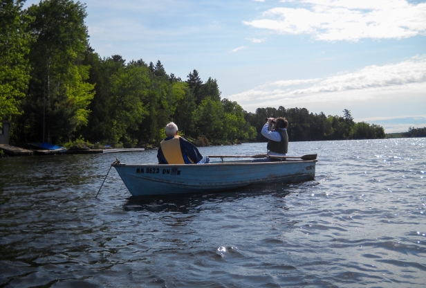 Two men in a blue fishing boat on a lake.