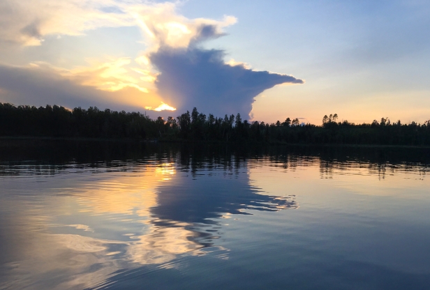 Cloud shaped like Minnesota is reflected in a calm lake.