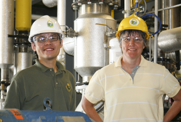Two people in an industrial setting wearting hard hats