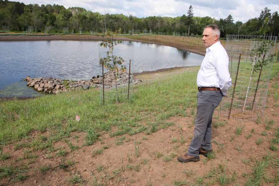 A man stands outside next to a pond in a stormwater garden.
