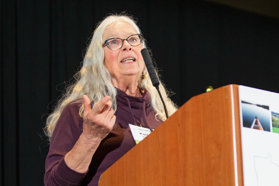 A woman standing at a podium and speaking into a microphone.