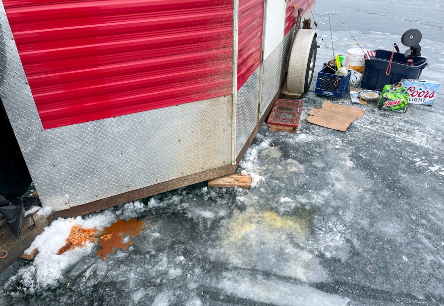 Garbage on the ice around an ice house.