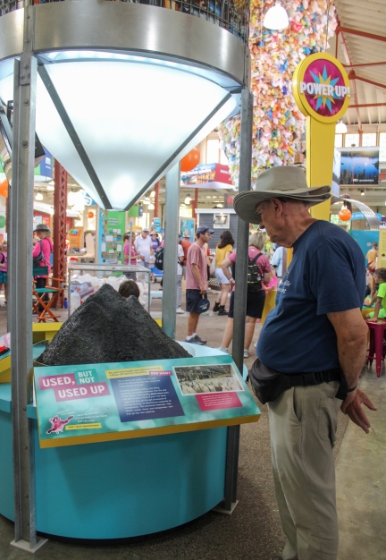 A man looks at an educational exhibit representing the "black mass" that recycled batteries become when they are crushed. 