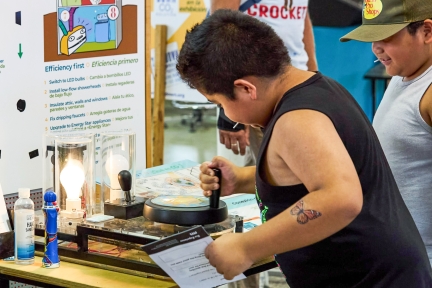 A boy turning a crank to power a light bulb.