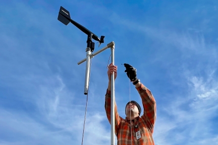 A man connecting a cable to air monitoring equipment. 