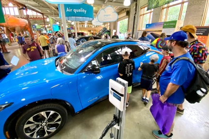 People looking at a blue electric vehicle.