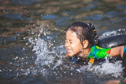 Girl in inflatable ring splashing in a lake.
