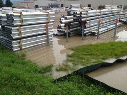 Stacks of long metal pipes in standing storm water.