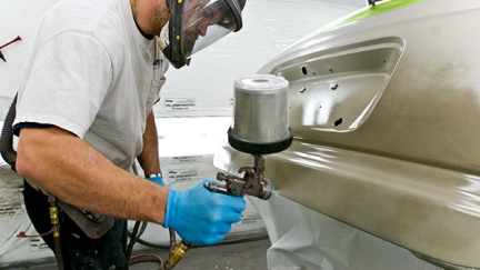 Man using a handheld-sprayer in auto repair setting