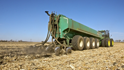 Tractor in field pulling tanker with manure injection equipment attached.