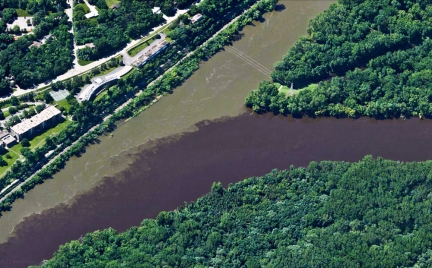 The Minnesota river colored light brown with sediment flows into the dark brown water of the Mississippi river