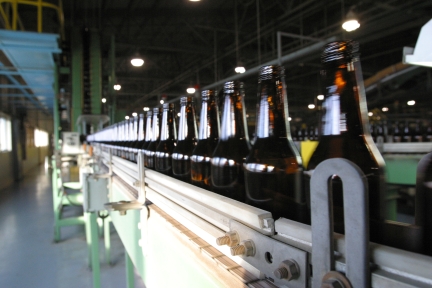Brown bottles made from recycled glass on a conveyor line. 