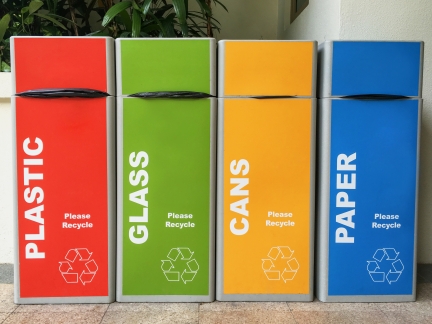 Four recycling bins marked plastic, glass, cans, and paper.