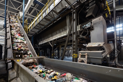 Conveyor belt at recycling plant transports garbage for sorting.
