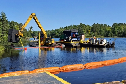 Excavator and other construction equipment on platforms in the water.