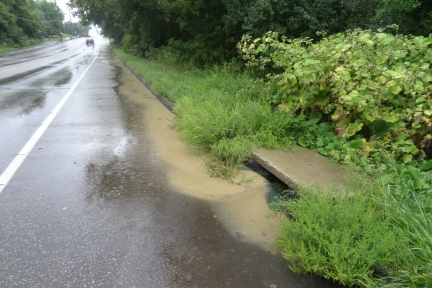 Water runoff carrying sediment into storm sewer along side of road.
