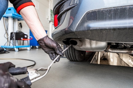 Person using equipment to test emissions from a car exhaust.