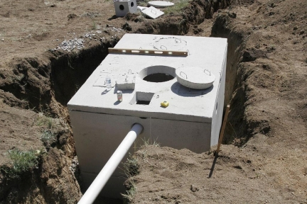 Subsurface sewage treatment tank in the ground.