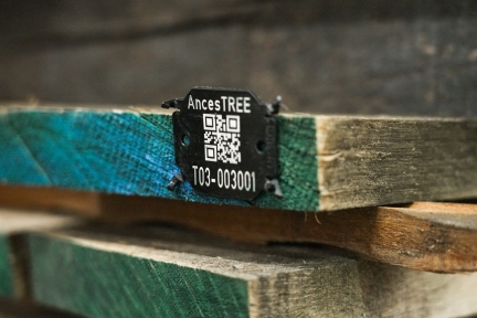 A black plastic tag with QR code attached to the end of a board.